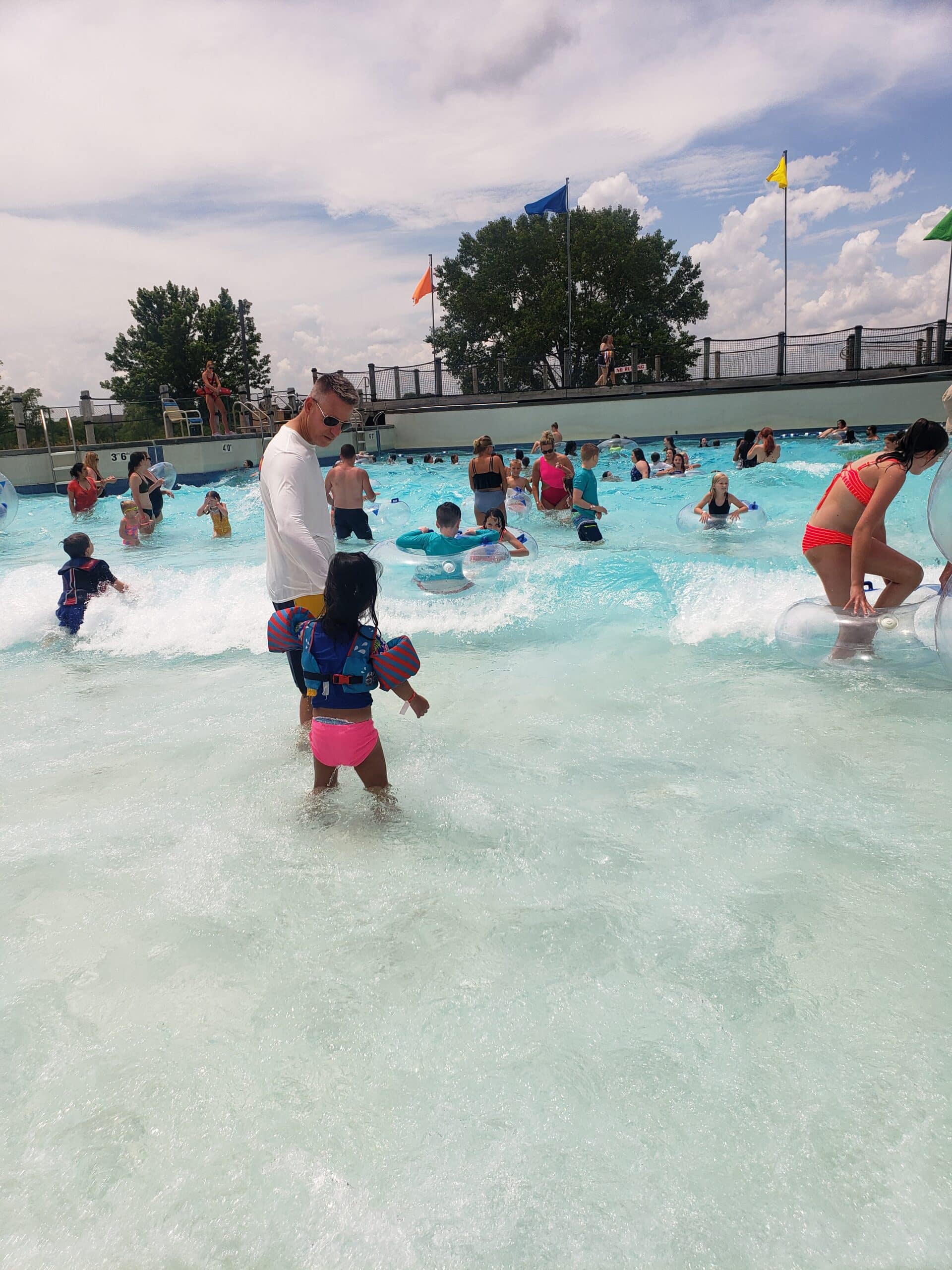 Children laughing and splashing in a wave pool at a popular waterpark near Omaha, enjoying summer fun under a sunny sky