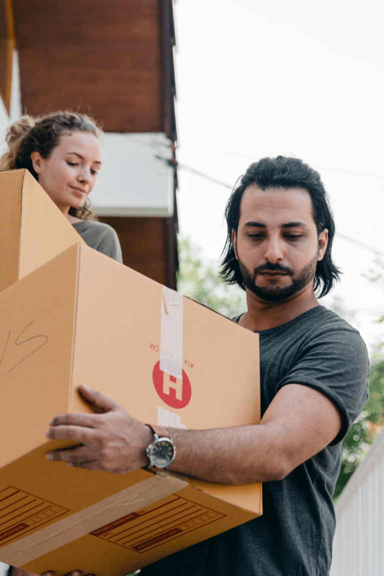 Man and woman carrying boxes down the stairs while moving to Sarpy County Nebraska, excited to settle into their new home."