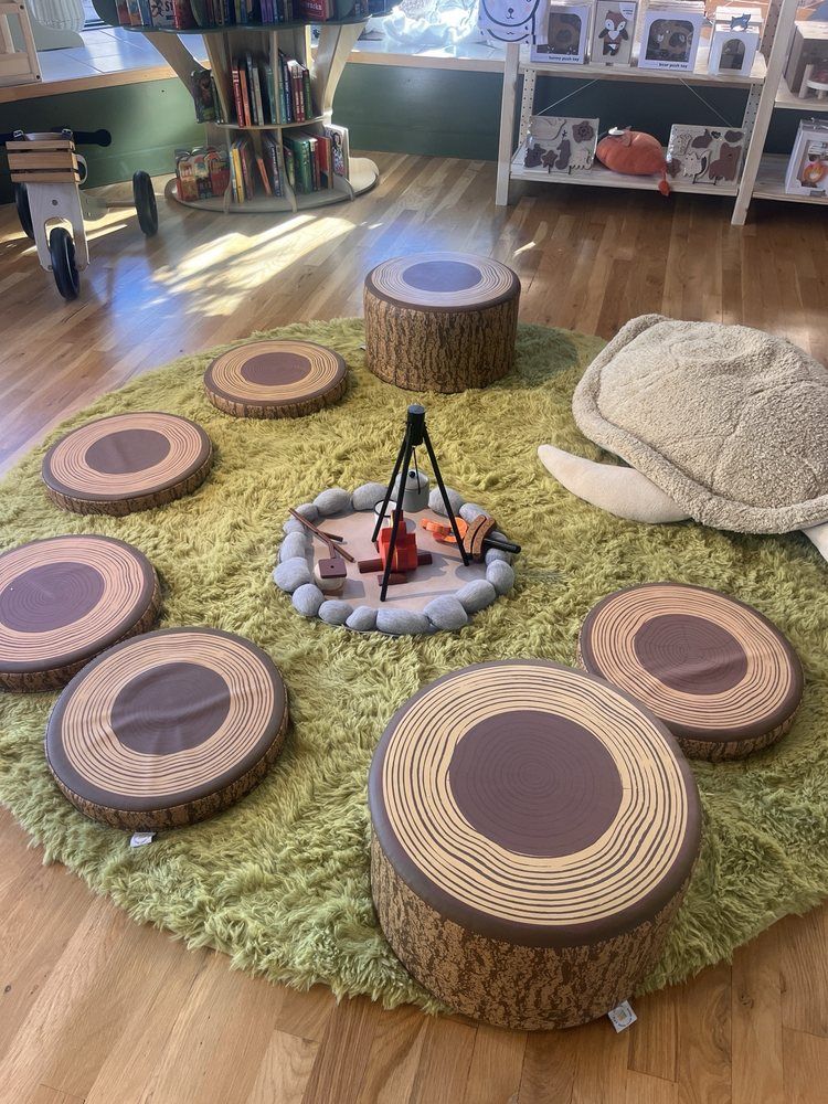Indoor play area at sensory-friendly toy store in Omaha featuring tree stump seats and artificial grass for imaginative, nature-inspired play.