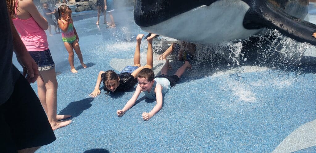 Child playing with water features at Alaskan Adventures splash pad, part of the best pools, splash pads and waterparks near Omaha for summer family fun.